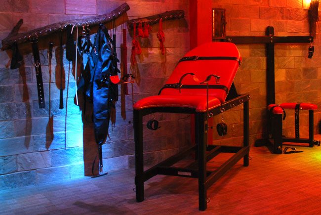 The Bondage Room — restraint bench and wall of equipment